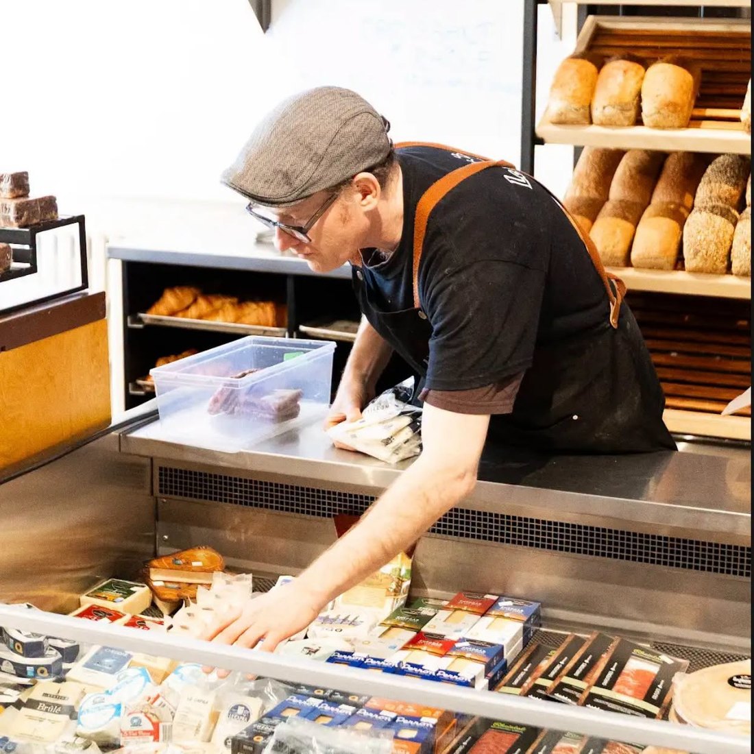 Un employé garnit le comptoir réfrigéré devant les étagères à pains